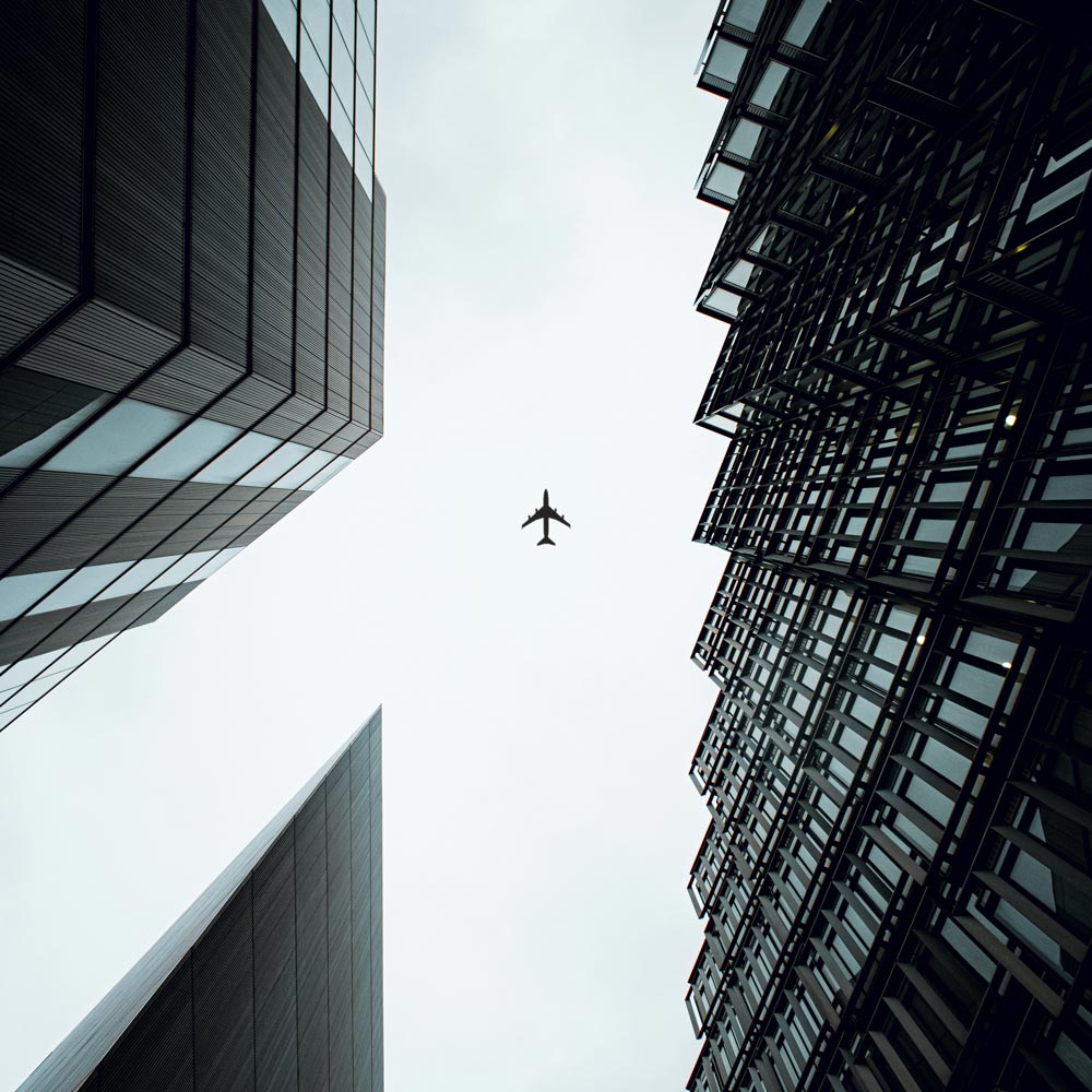 Airplane in the sky between buildings